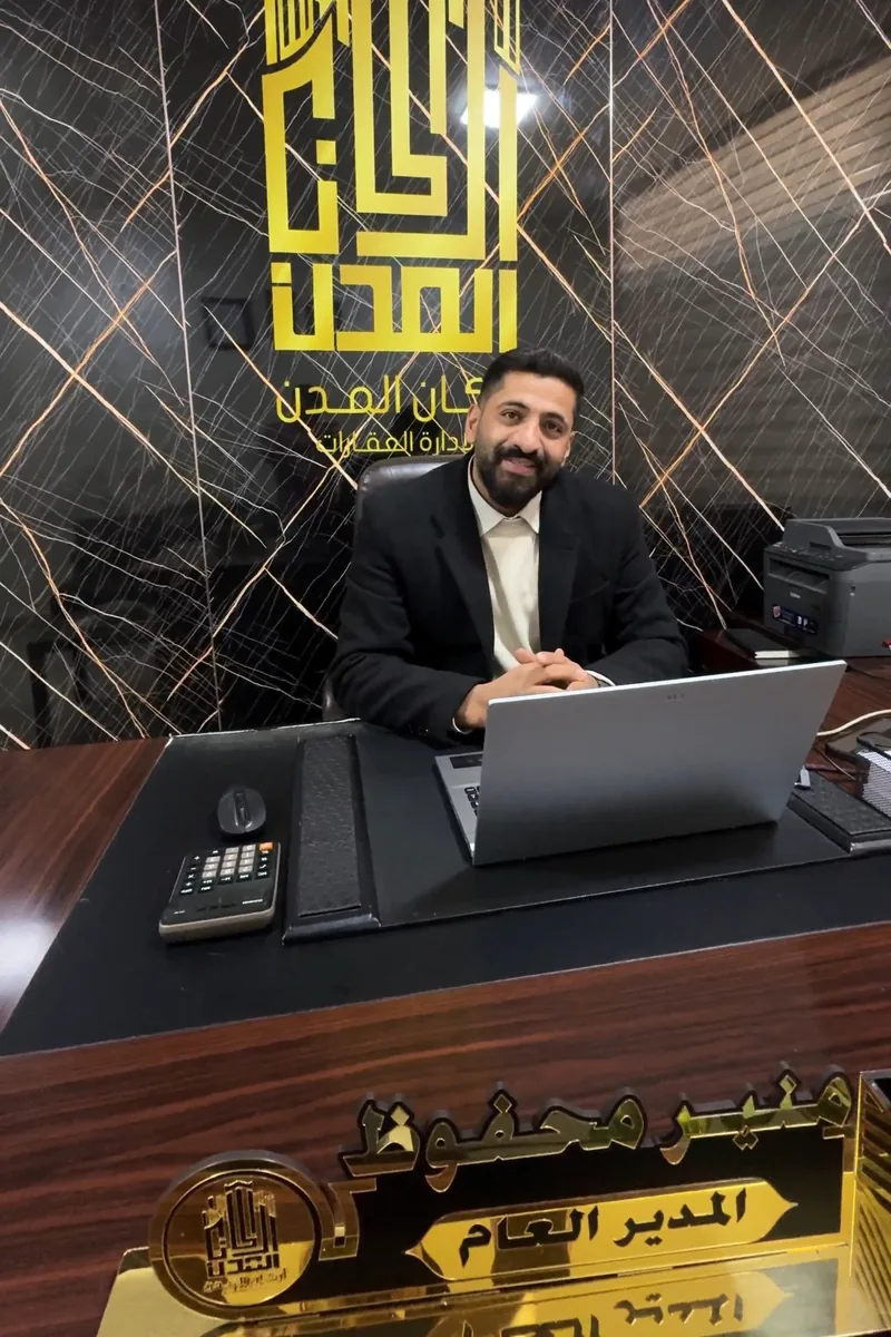 منير محفوظ في مكتب أركان المدن خلف لوحة اسمه